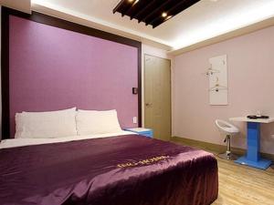 1 dormitorio con 1 cama grande y pared morada en Asan ING Hotel, en Asan