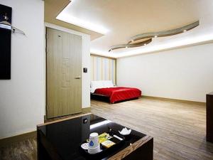 um quarto com uma cama vermelha num quarto em Asan ING Hotel em Asan