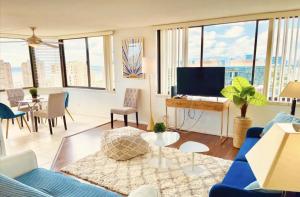 a living room with a blue couch and a tv at Hawaiian Monarch Penthouse 401 by Hawaii Ocean Club in Honolulu