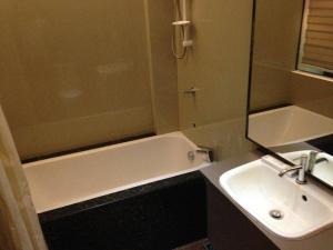 a bathroom with a sink and a bath tub and a mirror at Zanrock Micro Hotel in Lagao III