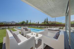 un patio con muebles blancos y una piscina en Villa Barcares, en Alcudia