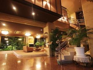 een lobby met een trap in een gebouw met potplanten bij Miyakonojo Sun Plaza Hotel in Miyakonojo