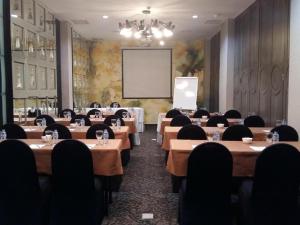 una sala conferenze con tavoli, sedie e schermo di Couleur Hotel Cengkareng a Giacarta