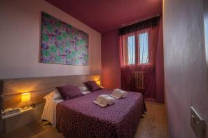 Hotel Palazzo Renieri - 3stelle S في كولّي فال ديلسا: غرفة نوم بسرير ارجواني عليها منشفتين