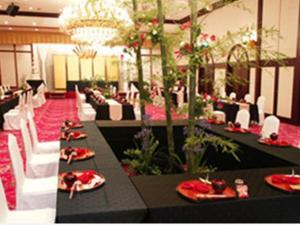 un salón de banquetes con mesas negras y sillas blancas en Miyakonojo Royal Hotel, en Miyakonojō