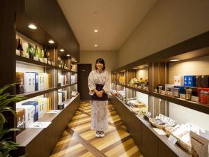 una mujer parada en el medio de un pasillo de una tienda en Yudaonsen Ubl Hotel Matsumasa, en Nakaichi