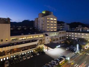 ein großes Gebäude mit Autos auf einem Parkplatz in der Unterkunft Yudaonsen Ubl Hotel Matsumasa in Nakaichi