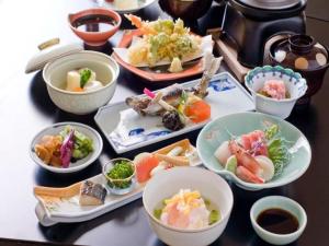 una mesa con platos de comida y cuencos de sushi en Takato Sakura Hotel en Ina