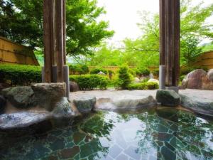 una piscina de agua en un jardín con rocas en Takato Sakura Hotel en Ina