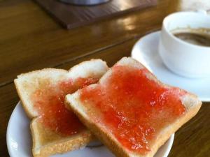 dos trozos de pan con mermelada en un plato con una taza de café en SabayNan Hotel en Ban Nong Tao