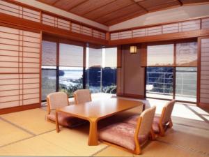 a dining room with a table and chairs and windows at Tomoyama Kanko Hotel in Azena