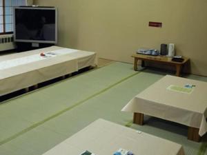 um quarto com duas camas e uma mesa e uma televisão em Yunosawa Onsen Mori no Shiki em Shimukappu