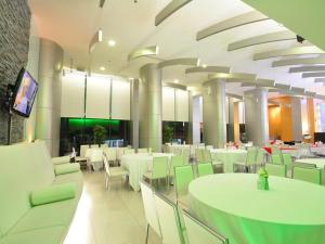 un restaurant avec des tables blanches et des chaises vertes dans l'établissement Mayflower Grande Hotel, à Hat Yai