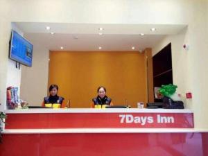 Dos mujeres están sentadas en recepción. en 7 Days Inn Yingshang Lanxing Building Materials Market, en Fuyang