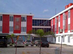 czerwono-biały budynek z samochodami zaparkowanymi na parkingu w obiekcie Le Man Hotel Lampung w mieście Umbulan Tulungmeris