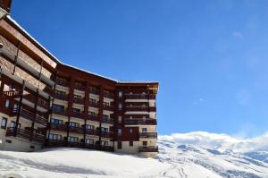 a building in the snow with mountains in the background at Résidence Necou - Studio pour 3 Personnes 954 in Les Menuires