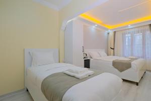Lucky Hotel İstanbul في إسطنبول: سريرين في غرفة بجدران بيضاء