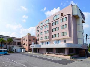 a pink building with a parking lot in front of it at Hotel New Otsuka in Shirako