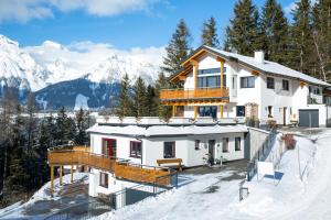 a house in the snow with mountains in the background at Appartement Wöhrer in Schladming