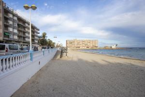 une plage avec une clôture blanche, des bâtiments et l'océan dans l'établissement ALEGRIA ID144, à Torrevieja