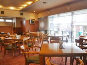 奥州市にあるMizusawa Grand Hotelのテーブルと椅子、大きな窓のあるレストラン