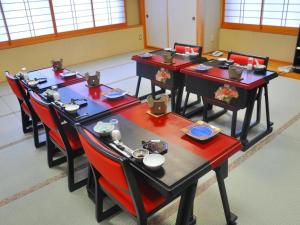 ein Esszimmer mit vier Tischen und roten Stühlen in der Unterkunft Senganishi Onsen Yumoto Azumakan in Oniyanagimachi