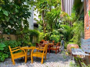 un patio con mesas y sillas, una mesa y bancos en BB House Mini Suite Hotel, en Ban Zong Katiam