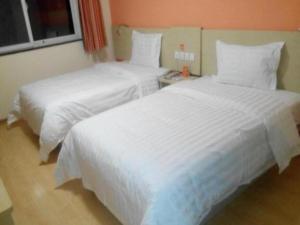 2 łóżka w pokoju hotelowym z białą pościelą w obiekcie 7 Days Inn Yan'an Baotashan w Yan'an