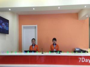 dwoje ludzi siedzących przy ladzie w pokoju w obiekcie 7 Days Inn Yan'an Baotashan w Yan'an