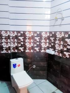een badkamer met een toilet met roze bloemen aan de muur bij Bharat Vandana Stay near Yashobhoomi in New Delhi
