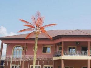 a palm tree in front of a pink building at BEVALUABLE BANQUET AND GARDENS in Alakohia