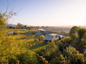 una caravana y una caravana estacionadas en un lado de la playa en Tāhuna Beach Holiday Park, en Nelson