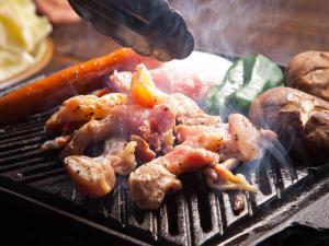a person grilling meat and vegetables on a grill at Yufuin Tsukahara Villa ERINA in Yufuin