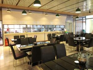 un restaurant avec des tables et des chaises et une cuisine dans l'établissement Pankun Business Hotel, à Kunming