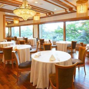 um restaurante com mesas e cadeiras brancas e um lustre em Hotel Grand Shinonome em Tsukuba