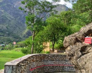 a stone bridge with a mountain in the background at Mashoo Resorts , Bhuntar in Shamshi