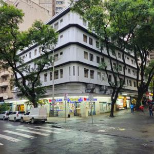 un gran edificio blanco en una calle de la ciudad con árboles en Hotel Turista, en Belo Horizonte