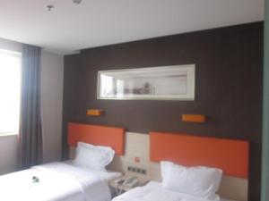 a hotel room with two beds and a mirror at 7 Days Premium Beijing Dabaotai Metro Station Luhua Road in Beijing