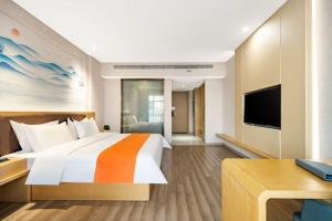 um quarto de hotel com uma cama grande e uma televisão em Huaian Reykana Hotel em Huai'an