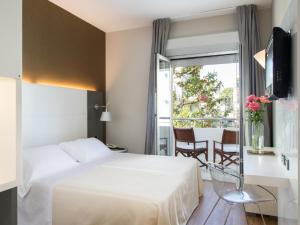 ein Hotelzimmer mit einem Bett, einem Tisch und einem Fenster in der Unterkunft Hotel Maddalena in Riccione