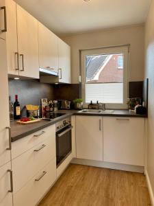 a large kitchen with white cabinets and a window at Ferienwohnung Dünenbutze in Büsum