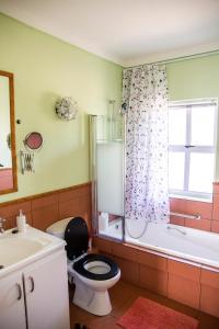 een badkamer met een toilet, een bad en een wastafel bij Home @ Eleven in Jeffreys Bay