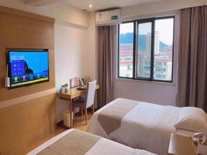 a hotel room with two beds and a desk with a television at GreenTree Inn Xuancheng Jingxian Wannan First Street Express Hotel in Jingxian
