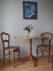 una mesa con dos sillas y un jarrón con flores. en St Michel, en Vains