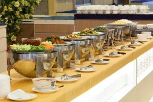 een buffetlijn met borden en kommen met eten bij Aurora Bay Hotel in Bangna
