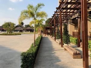 a walkway with palm trees next to a building at Pawa Place (By Inpawa) in Ban Phai