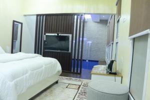 Dormitorio con cama, TV y taburete en D, en Al Ḩamrāʼ