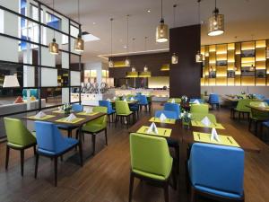 Yuangengshang的住宿－Hampton by Hilton Suzhou XiangCheng，餐厅设有蓝色和绿色的桌椅