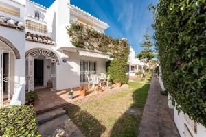 a white house with a yard with plants at La Cala Mijas Playa Club in La Cala de Mijas