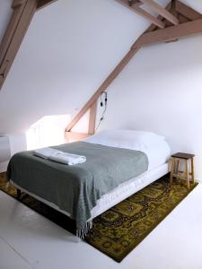 - une chambre blanche avec un lit et une couverture verte dans l'établissement Appartement cosy chic La Ville au Monnier, à Pleurtuit